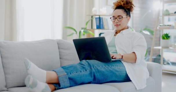 Woman relax on couch with laptop for internet, online streaming or freelance networking in her apartment. Work from home, break and happy biracial person on sofa in living room working on computer. - Filmati, video