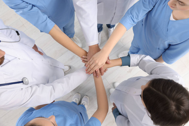 Team of medical doctors putting hands together indoors, above view - Fotó, kép