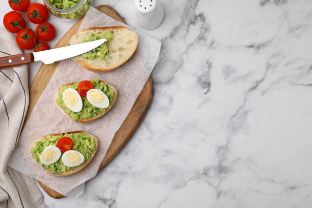 Delicious sandwiches with guacamole, eggs and tomatoes on white marble table, flat lay. Space for text - Фото, зображення