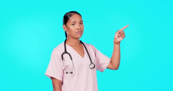 Woman, doctor and point in studio for mockup, healthcare decision or tips menu by blue background. Young female medic, pointing or portrait for disagree, mock up space or advice for bad health habits. - Materiaali, video