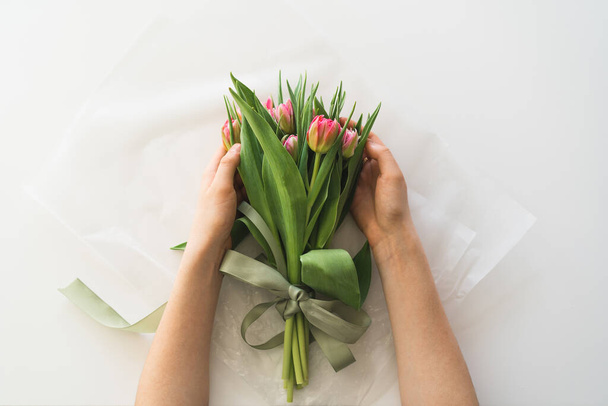 Womans hands holding bouquet of beautiful delicate tulip flowers on white background. Bouquet of pink fresh tulips. - Foto, Imagem