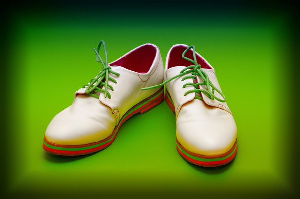 Fashion leather shoes in white with green shoelaces on a green background - Photo, Image