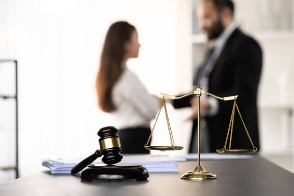 Balanced scale of justice and gavel hammer in focus on blurred background of lawyer colleagues discuss and plan for lawsuit in law firm office, as legal representatives. Equilibrium - Foto, Imagen