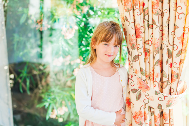 Indoor portrait of a cute little girl standing by the window - Photo, Image
