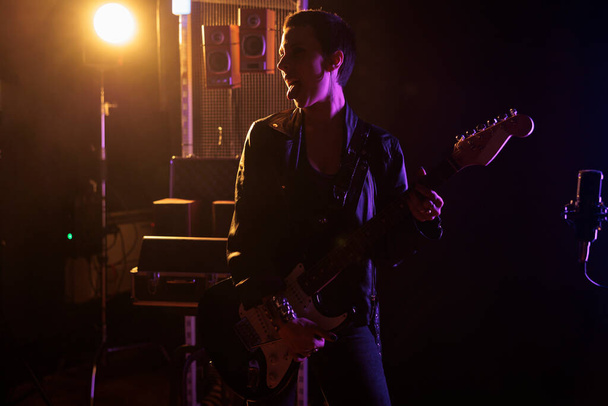 Гитарист-музыкант играет рок-музыку в звукозаписывающей студии с использованием электрогитары во время записи нового гранж-альбома. Рэбель Хемсворт, звезда хэви-метала, перед выступлением в клубе - Фото, изображение