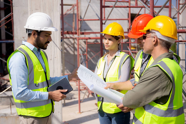 Team group of contractor and architect with foreman explaining about scheme building site for planning project to worker and looking blueprint, construction site, development and structure. - Photo, Image