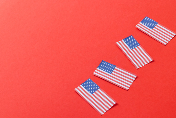 High angle view of four flags of united states of america with copy space on red background. American patriotism, independence day and tradition concept. - Foto, Imagen