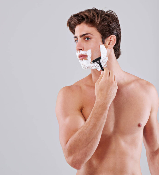 Now thats a close shave. Studio shot of a handsome bare chested young man shaving - Zdjęcie, obraz