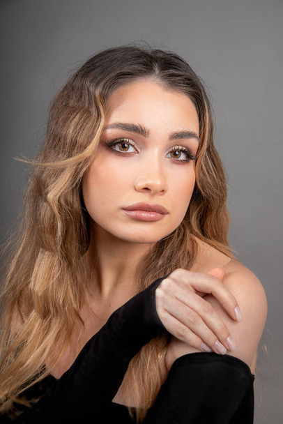 Close-up portrait of face of young beautiful model with long well-groomed hair and professional makeup, in off-the-shoulder dress. Skin and hair care. Professional makeup artist. Beauty salon. - Foto, Bild