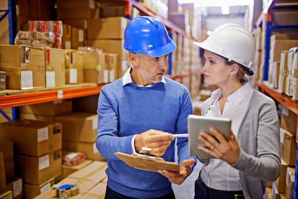 Lets get this order shipped immediately. a man and woman inspecting inventory in a large distribution warehouse - Foto, Bild