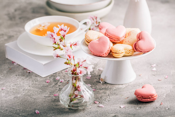 Macarrones o macarrones franceses en forma de corazón con té con pétalos de flor de cerezo para el Día de las Madres - Foto, imagen