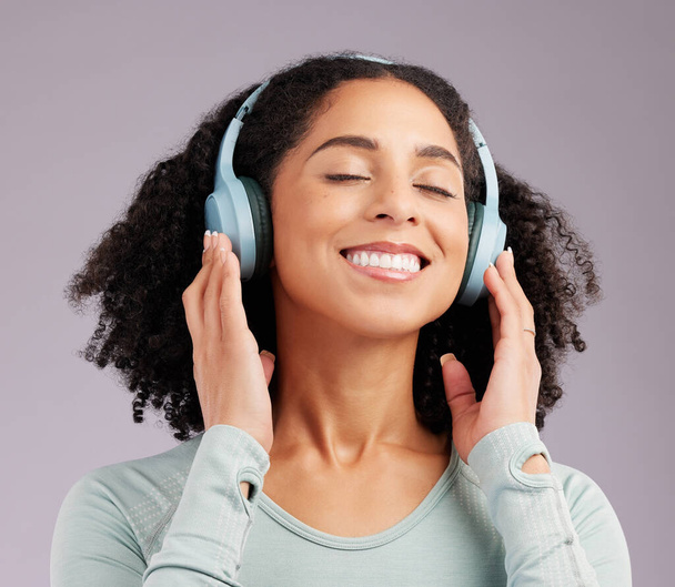 Gelukkige vrouw, koptelefoon en glimlach luisteren naar muziek in vreugde tegen een grijze studio achtergrond. Plezier en rust vrouwelijke glimlachen en ontspannen in geluk met headset voor audio track, geluid of podcast. - Foto, afbeelding