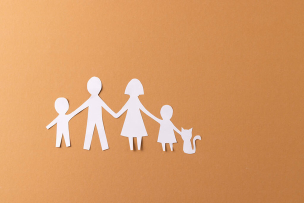 White paper cut out of family with two children and ca and copy space on brown background. Humanitarian aid, people, help and human concept. - Fotó, kép