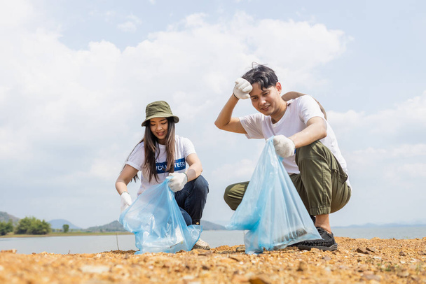 Voluntários masculinos e femininos coletando lixo, conduzindo cooperação ambiental, economizando o aquecimento global, Voluntários limpam resíduos de sacos de plástico em atrações naturais. - Foto, Imagem