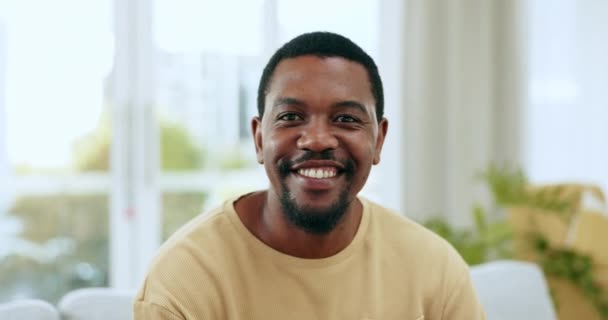 Gelukkig, glimlachen en ontspannen met zwarte man op de bank voor vrije tijd, positief en tevredenheid. Weekend, geluk en rust met portret van een man in de woonkamer thuis voor lounge, ochtend en lifestyle. - Video