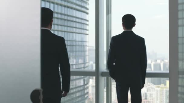 két ázsiai üzletember beszélgetett, miközben nézték a várost az iroda ablaka előtt. - Felvétel, videó