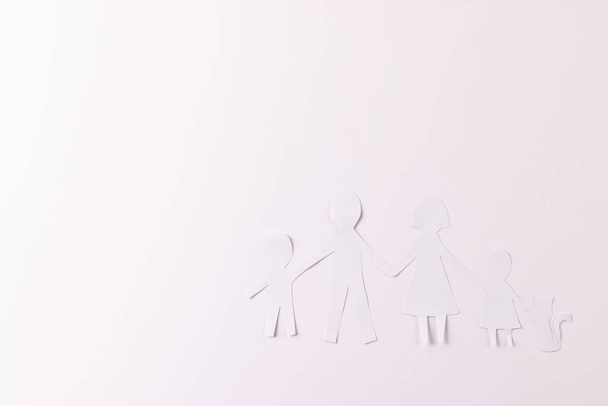 White paper cut out of family with two children and cat and copy space on white background. Humanitarian aid, people, help and human concept. - Zdjęcie, obraz