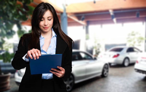 Beautiful car dealer reading a contract - Фото, зображення