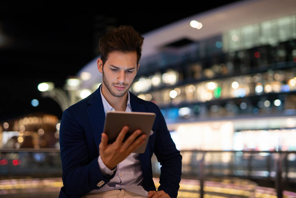Portrait of young business man using his tablet in a city at night - Foto, immagini