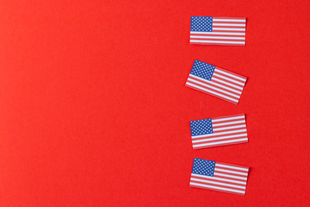 High angle view of four flags of united states of america with copy space on red background. American patriotism, independence day and tradition concept. - Foto, afbeelding