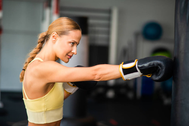 Woman training on the punching bag in a gym, fitness concept - Photo, Image