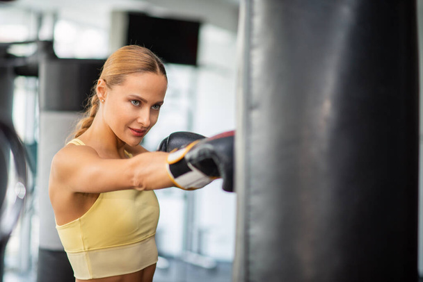 Entraînement de femme sur le sac de boxe dans une salle de gym, concept de fitness - Photo, image