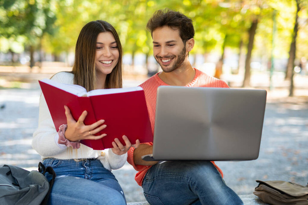 College students using a laptop computer in a park, young people and technology concept - Photo, image