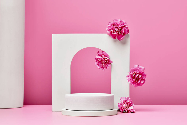 white podium with pink flowers and elegant arch isolated on pastel pink background. stage for presentation cosmetic or beauty product. minimal fashion design - Foto, afbeelding
