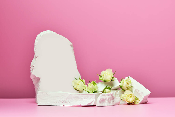 ピンクの背景に白い石と白いバラが孤立しています。表彰台製品や化粧品の - 写真・画像