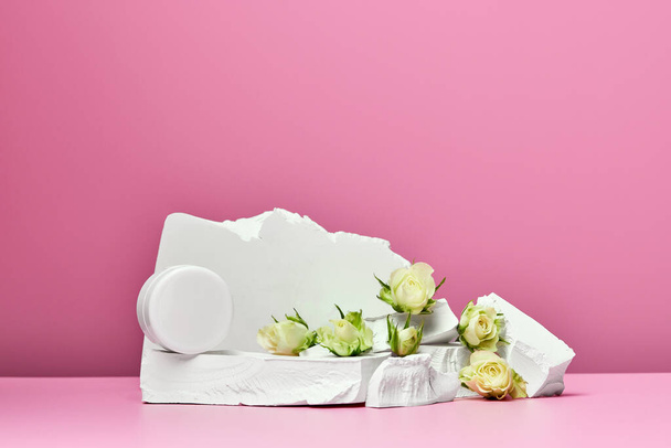 White jar of cream with stones and white roses isolated on pink background - Photo, Image