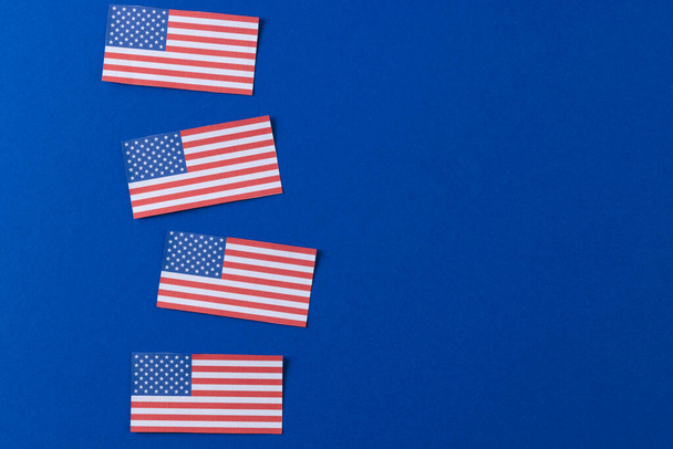 High angle view of four flags of united states of america with copy space on blue background. American patriotism, independence day and tradition concept. - Photo, image