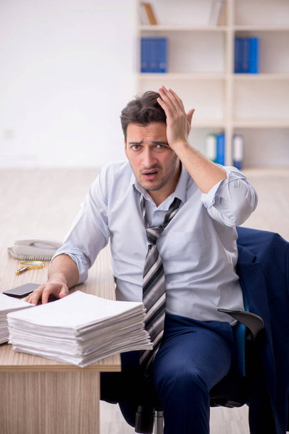 Young employee and too much work at workplace - Photo, image