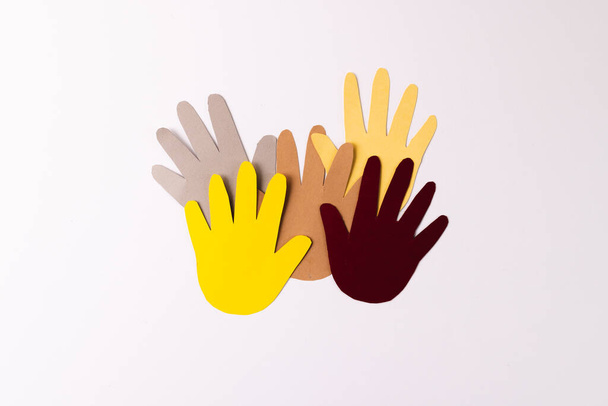 Paper cut out of multi coloured hands with copy space on white background. Humanitarian aid, people, help and human concept. - 写真・画像