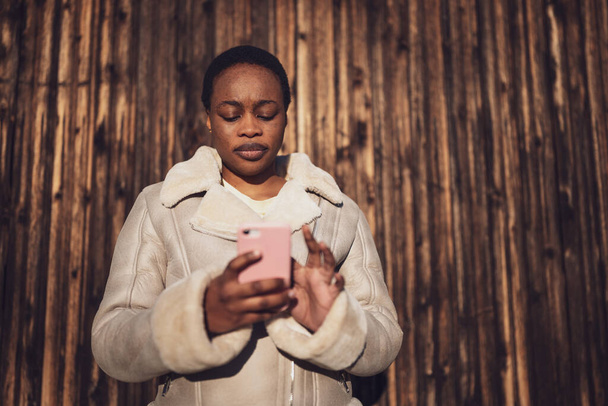 Muotokuva afrikkalais-amerikkalaisesta naisesta. Hän viestii älypuhelimella.. - Valokuva, kuva