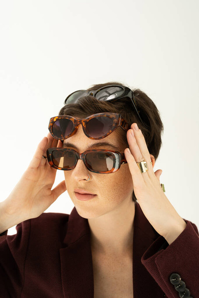  retrato de mujer de moda con diferentes gafas de sol de moda aisladas en gris - Foto, Imagen