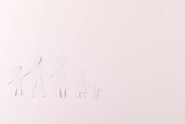White paper cut out of family with two children and cat and copy space on white background. Humanitarian aid, people, help and human concept. - Fotó, kép