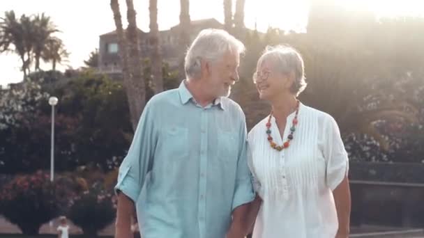 riprese di due anziani o pensionati felici e attivi che si divertono e si divertono guardando il tramonto sorridente con il mare - anziani all'aperto che si godono le vacanze insieme - Filmati, video