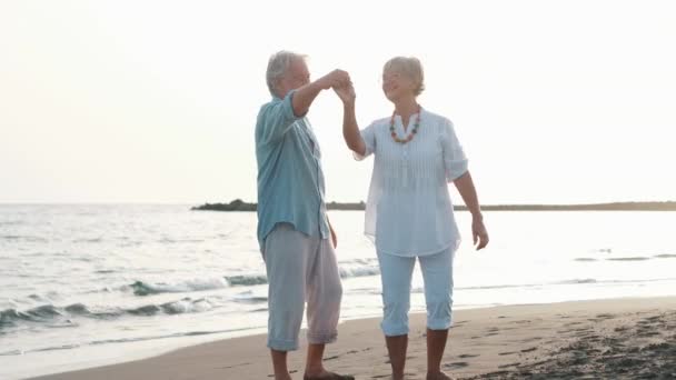 imágenes de dos jubilados o pensionistas felices y activos divirtiéndose y disfrutando mirando el atardecer sonriendo con el mar - ancianos al aire libre disfrutando de vacaciones juntos - Metraje, vídeo
