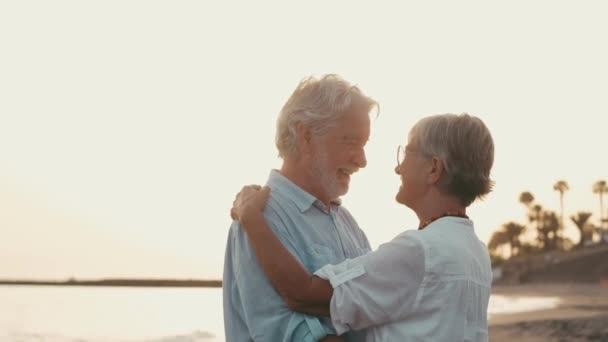 imagens de dois idosos felizes e ativos ou pensionistas se divertindo e desfrutando de olhar para o pôr do sol sorrindo com o mar - idosos ao ar livre desfrutando de férias juntos - Filmagem, Vídeo