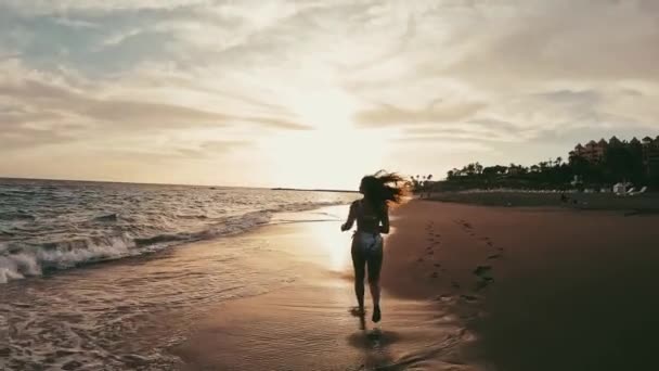 Güzel genç bir kadının günbatımı kumsalında yürüyüşünün görüntüleri. - Video, Çekim