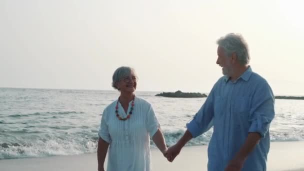 záběry dvou šťastných a aktivních seniorů nebo důchodců, kteří se baví a užívají si při pohledu na západ slunce, usmívají se s mořem - staří lidé spolu tráví dovolenou venku - Záběry, video