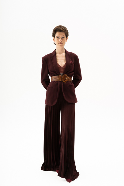 full length of elegant woman in blazer and wide pants standing on white background - Foto, Bild