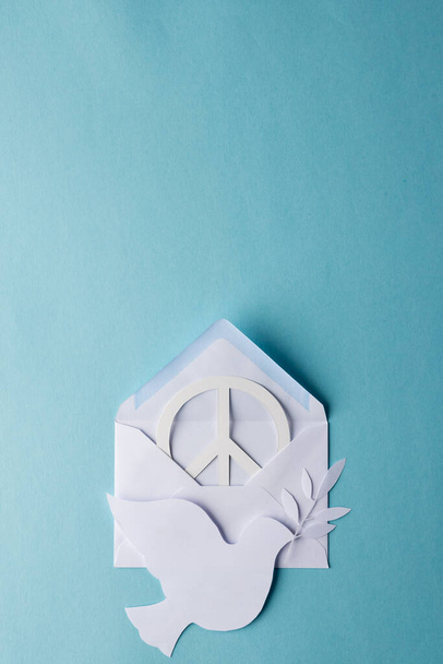 High angle view of white peace sign, white dove and envelope with copy space on blue background. Peace and anti war movement concept. - Foto, Bild