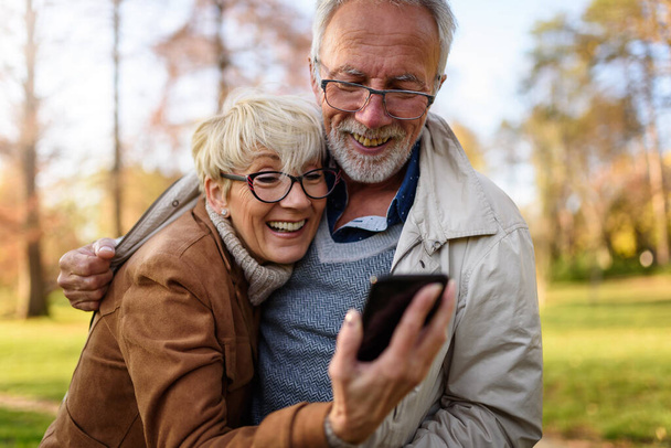 šťastný starší pár dělat selfie v parku - Fotografie, Obrázek