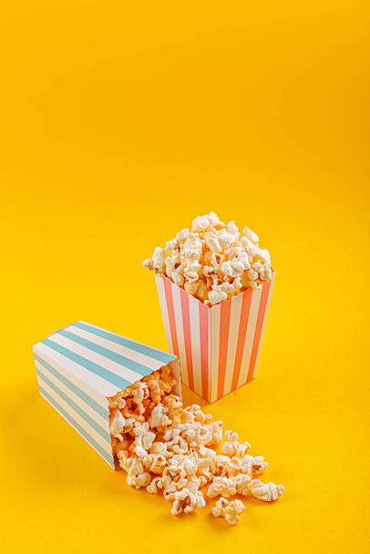Glass with popcorn on a yellow background close-up - Фото, зображення