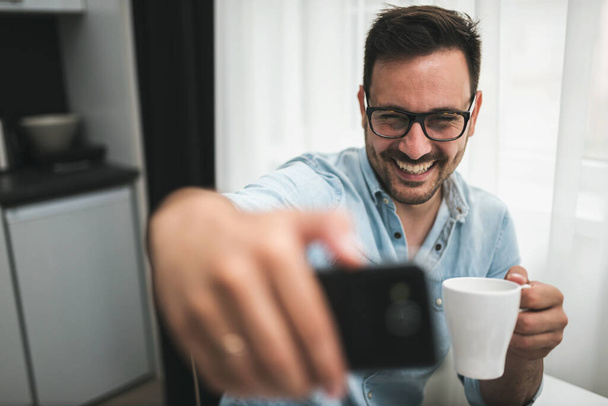 jóképű fiatalember egy csésze kávéval otthon - Fotó, kép