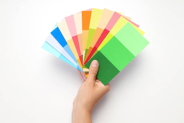 Female hand holding color palettes on white background - Фото, изображение