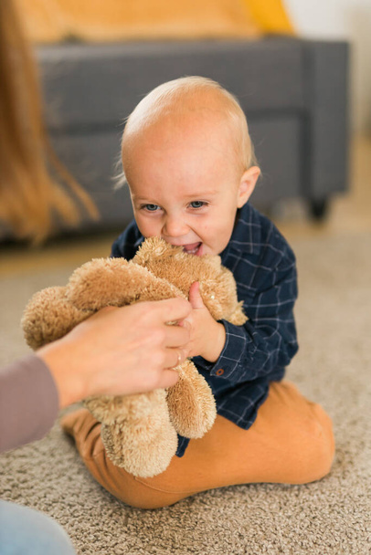 Felice bambino bambino che gioca con il suo orsacchiotto a casa - infanzia e fasi di sviluppo del bambino - Foto, immagini