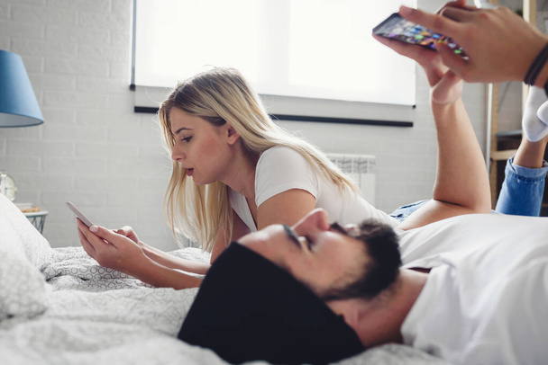 coppia sdraiata a letto con i telefoni - Foto, immagini