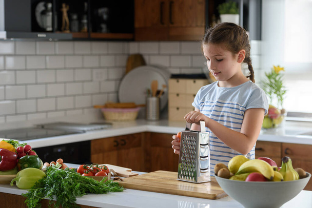 Mladá hezká dívka pomáhá v kuchyni připravuje zdravé vegetariánské jídlo - Fotografie, Obrázek
